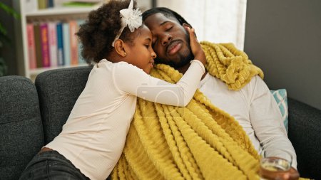 Téléchargez les photos : Afro-américain père et fille être malade prendre soin de l'homme à la maison - en image libre de droit