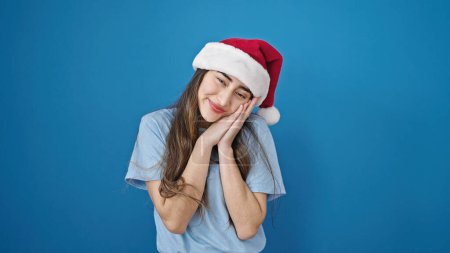 Téléchargez les photos : Jeune belle femme hispanique souriant confiant portant un chapeau de Noël sur fond bleu isolé - en image libre de droit