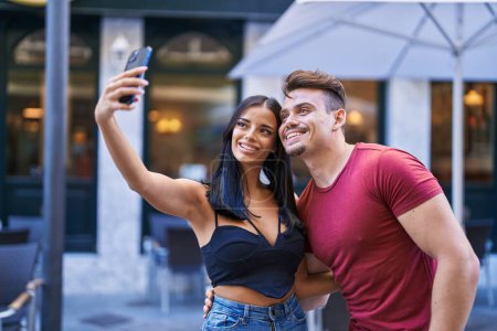Téléchargez les photos : Homme et femme couple souriant confiant faire selfie par smartphone à la terrasse du café - en image libre de droit