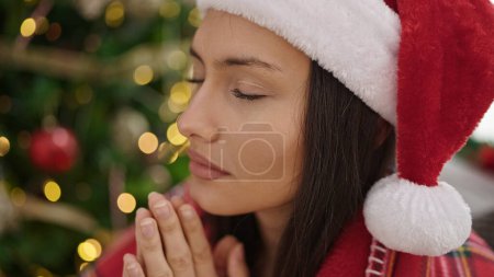 Téléchargez les photos : Jeune belle femme hispanique célébrant Noël en priant à la maison - en image libre de droit