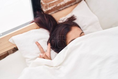 Téléchargez les photos : Jeune belle femme hispanique couvrant avec drap de lit faisant geste de victoire avec les doigts dans la rue - en image libre de droit