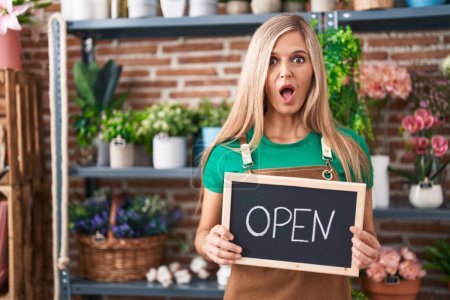 Photo for Young woman working at florist holding open sign afraid and shocked with surprise and amazed expression, fear and excited face. - Royalty Free Image