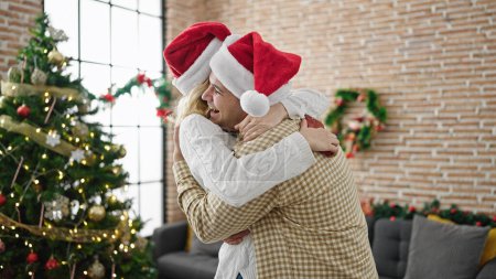 Foto de Hombre y mujer pareja abrazándose celebrando la Navidad en casa - Imagen libre de derechos