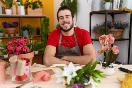 Téléchargez les photos : Jeune homme hispanique travaillant à la boutique de fleuriste avec un sourire heureux et cool sur le visage. chanceux. - en image libre de droit