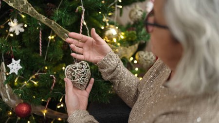 Téléchargez les photos : Femme d'âge moyen avec des cheveux gris décorant arbre de Noël à la maison - en image libre de droit
