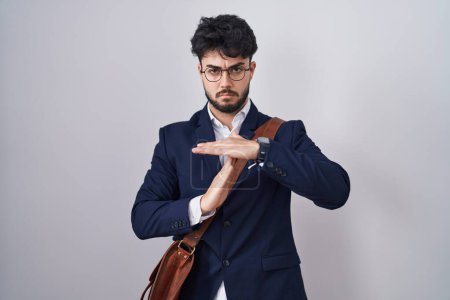 Téléchargez les photos : Homme hispanique avec barbe portant des vêtements de travail faire le temps geste avec les mains, visage frustré et sérieux - en image libre de droit