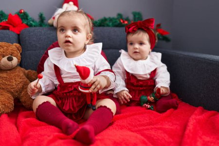 Photo for Adorable girls sitting on sofa celebrating christmas at home - Royalty Free Image