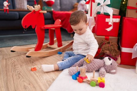 Photo for Adorable caucasian baby sitting on floor by christmas gifts playing at home - Royalty Free Image