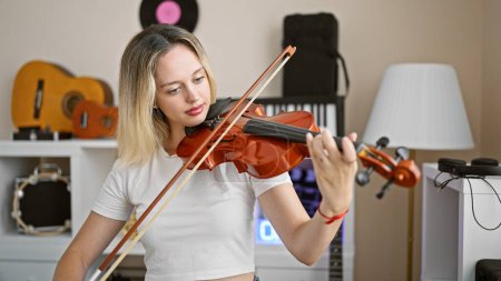 Photo for Young blonde woman musician playing violin at music studio - Royalty Free Image
