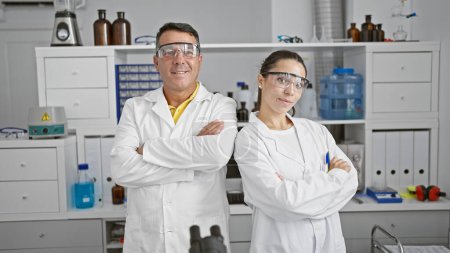 Foto de Hombres y mujeres científicos sonrientes con brazos cruzados en el laboratorio, socios felices en el mundo de la investigación - Imagen libre de derechos