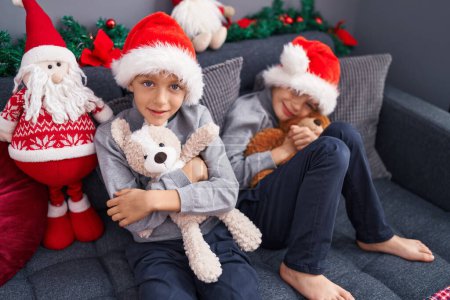 Téléchargez les photos : Adorables garçons embrassant ours en peluche célébrant Noël à la maison - en image libre de droit