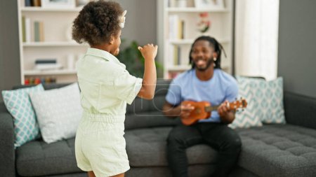 Photo for African american father and daughter playing ukulele dancing at home - Royalty Free Image