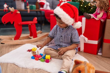 Photo for African american boy playing with toy sitting on floor by christmas gifts at home - Royalty Free Image