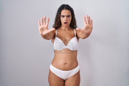 Photo for Young hispanic woman wearing white lingerie doing stop gesture with hands palms, angry and frustration expression - Royalty Free Image