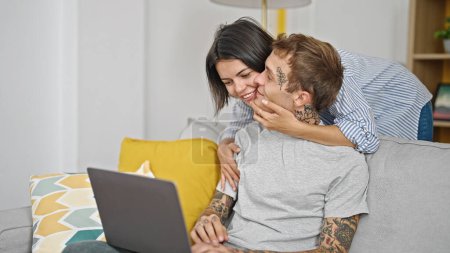 Photo for Beautiful couple hugging each other using laptop at home - Royalty Free Image