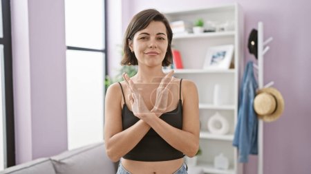 Photo for Stunning young hispanic woman adamantly displays stop gesture with arms at home, expressing refusal in her beautifully furnished living room. - Royalty Free Image
