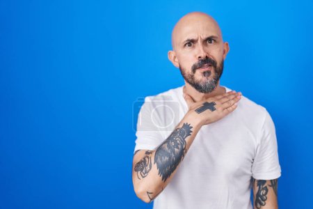 Téléchargez les photos : Homme hispanique avec des tatouages debout sur fond bleu couper la gorge avec la main comme couteau, menacer d'agression avec une violence furieuse - en image libre de droit