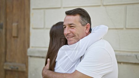 Photo for Confident father shares a hearty, smiling hug with his daughter on a sunny city street, their happy, casual lifestyle radiating love and joy in the outdoors. - Royalty Free Image