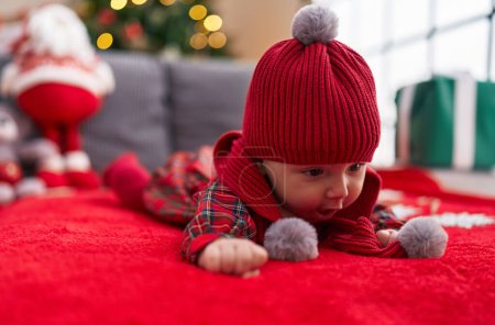 Photo for Adorable caucasian baby lying on sofa by christmas tree at home - Royalty Free Image