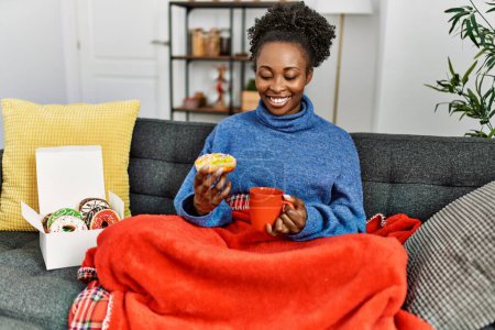 Foto de Mujer afroamericana desayunando sentada en el sofá en casa - Imagen libre de derechos