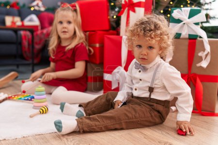Photo for Adorable boy and girl playing with xylophone and car toy celebrating christmas at home - Royalty Free Image