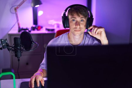 Photo for Young caucasian man streamer smiling confident sitting on table at gaming room - Royalty Free Image
