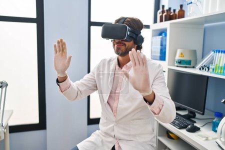 Foto de Middle age man scientist using virtual reality glasses at laboratory - Imagen libre de derechos