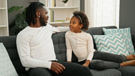 Téléchargez les photos : Père et fille afro-américains assis sur le canapé parlant à la maison - en image libre de droit