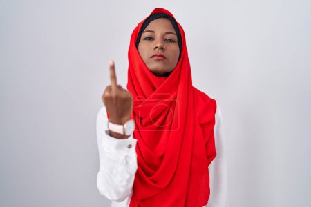 Photo for Young arab woman wearing traditional islamic hijab scarf showing middle finger, impolite and rude fuck off expression - Royalty Free Image