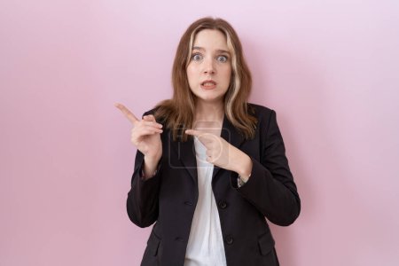 Téléchargez les photos : Jeune femme d'affaires caucasienne portant une veste noire pointant de côté inquiet et nerveux avec les deux mains, préoccupé et expression surprise - en image libre de droit