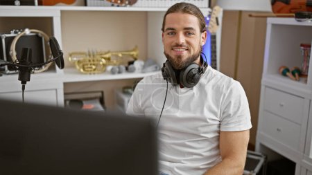 Téléchargez les photos : Jeune homme hispanique musicien portant un casque souriant au studio de musique - en image libre de droit