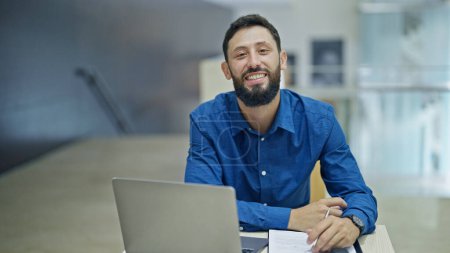 Photo for Young hispanic man business worker using laptop taking notes at the office - Royalty Free Image