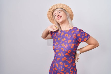 Téléchargez les photos : Jeune femme caucasienne portant des fleurs robe et chapeau d'été étirant le dos, fatigué et détendu, somnolent et bâillant pour tôt le matin - en image libre de droit