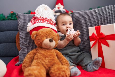 Téléchargez les photos : Adorable bambin hispanique assis sur le canapé par la décoration de Noël à la maison - en image libre de droit