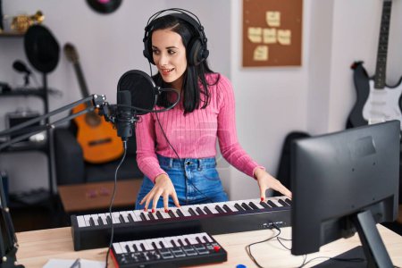 Foto de Joven mujer caucásica músico cantando canción tocando el piano en el estudio de música - Imagen libre de derechos