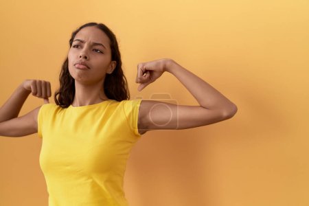Photo for Young african american woman smiling confident doing strong gesture with arms over isolated yellow background - Royalty Free Image