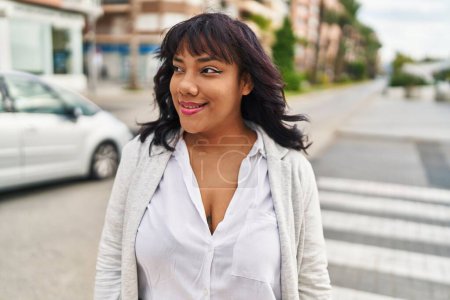 Téléchargez les photos : Jeune belle femme latine souriante confiante regardant du côté de la rue - en image libre de droit