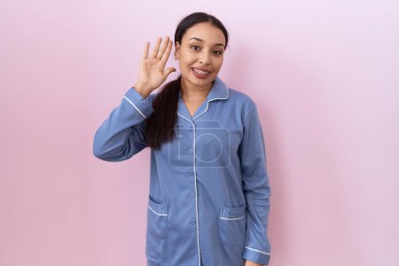 Photo for Young arab woman wearing blue pajama waiving saying hello happy and smiling, friendly welcome gesture - Royalty Free Image