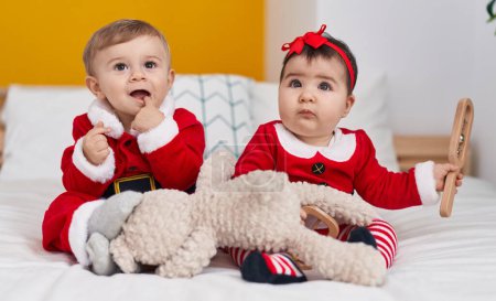 Photo for Adorable boy and girl wearing christmas clothes sitting on bed at bedroom - Royalty Free Image