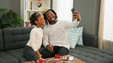 Téléchargez les photos : Afro-américain père et fille portant roi couronne et baggy yeux pad faire selfie par smartphone à la maison - en image libre de droit