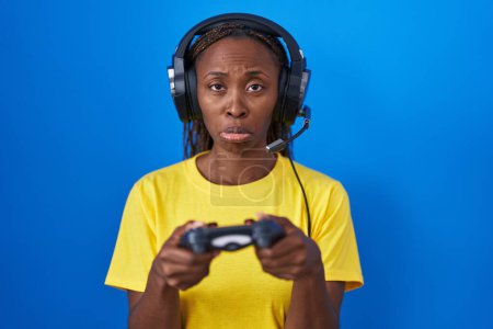 Photo for African american woman playing video games depressed and worry for distress, crying angry and afraid. sad expression. - Royalty Free Image