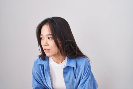 Téléchargez les photos : Jeune femme chinoise debout sur fond blanc avec la main sur le ventre parce que l'indigestion, la maladie douloureuse se sent mal. concept de douleur. - en image libre de droit