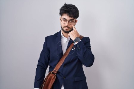 Téléchargez les photos : Homme hispanique avec barbe portant des vêtements de travail pointant vers l'œil vous regardant geste, expression suspecte - en image libre de droit