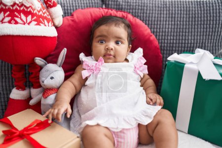 Téléchargez les photos : Bébé afro-américain assis sur un canapé par des cadeaux de Noël à la maison - en image libre de droit