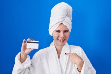 Photo for Blonde caucasian woman wearing bathrobe holding credit card pointing finger to one self smiling happy and proud - Royalty Free Image