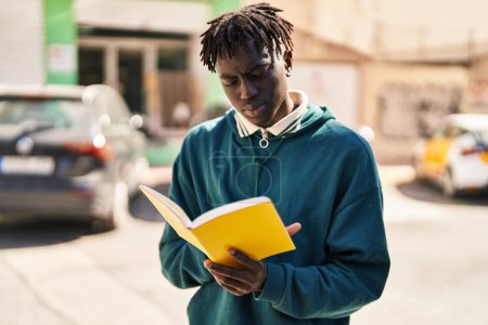 Téléchargez les photos : African american man reading book at street - en image libre de droit