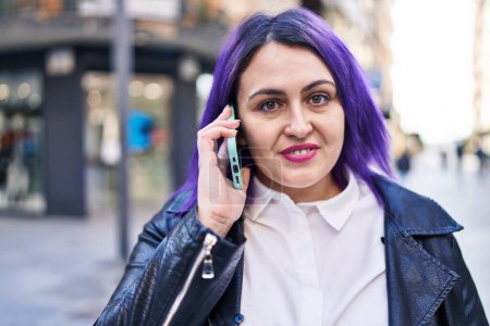 Téléchargez les photos : Jeune belle plus la taille femme souriant confiant parler sur le smartphone à la rue - en image libre de droit