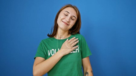 Téléchargez les photos : Jeune femme volontaire souriant confiant avec la main sur le cœur sur fond bleu isolé - en image libre de droit