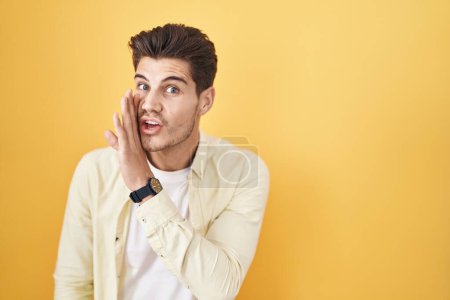 Photo for Young hispanic man standing over yellow background hand on mouth telling secret rumor, whispering malicious talk conversation - Royalty Free Image