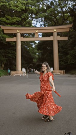 Photo for Joyful hispanic woman smiling with open arms, looking around at meiji temple, showcasing confidence and happiness - Royalty Free Image